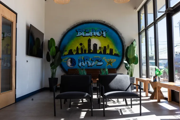 The waiting area with the Bishop Arts mural, black chairs, plants and morning light