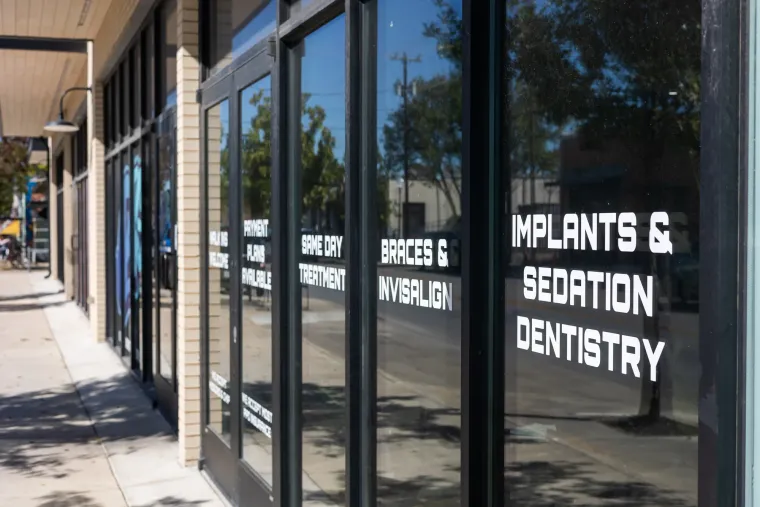 Storefront window decals reading walk ins welcome, same day treatment, braces and Invisalign, implants and sedation dentistry