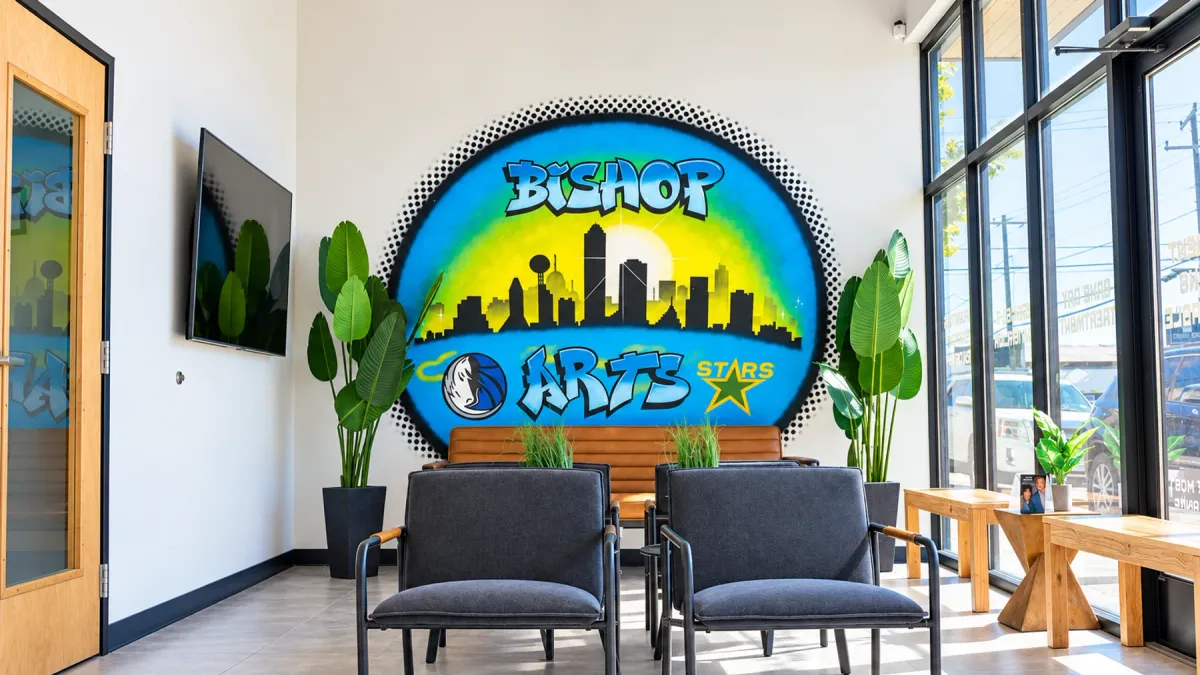 The Arts Family Dentistry waiting room in Bishop Arts, with the hand-painted Dallas skyline mural above the leather bench