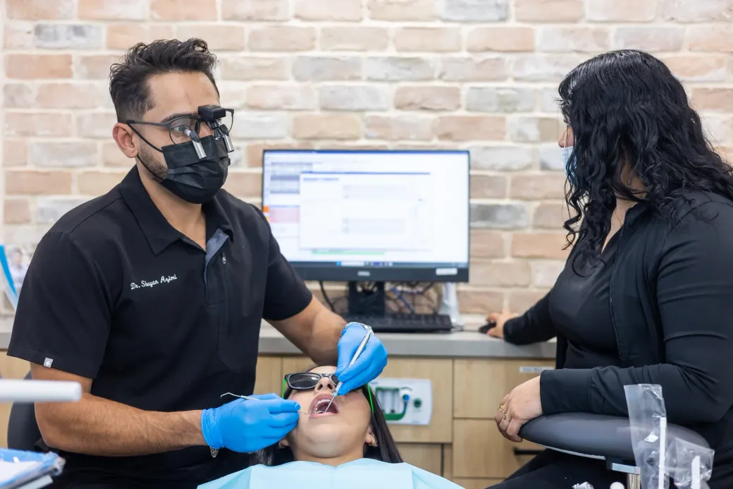 Dr. Shayan Azimi in loupes and a mask treating a patient in the chair