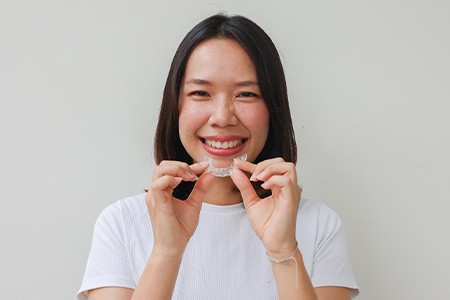 Woman smiling while holding clear aligner