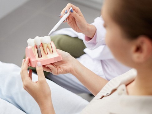 A dentist showing a patient a dental implant model