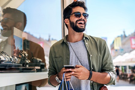 Man with sunglasses smiling while shopping outside