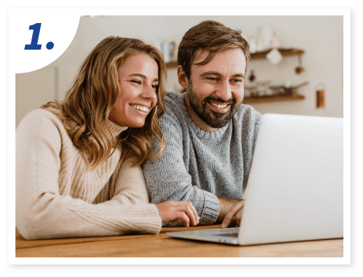 A smiling couple looks at a laptop screen together.