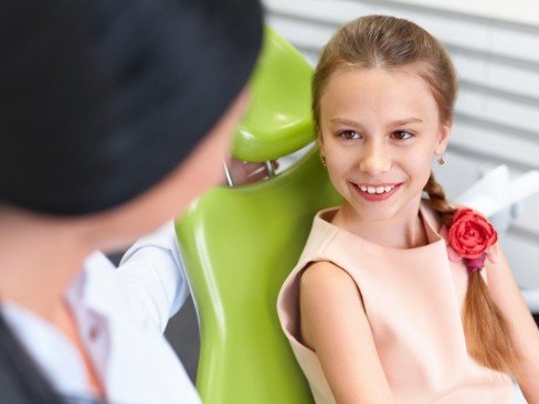 Child in dental chair smiling at dentist