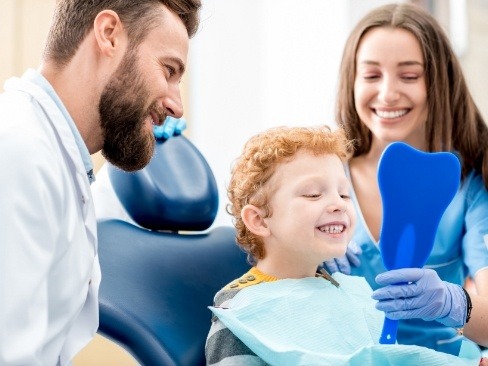 Dentist and child smiling together thanks to dental checkup and teeth cleaning visit