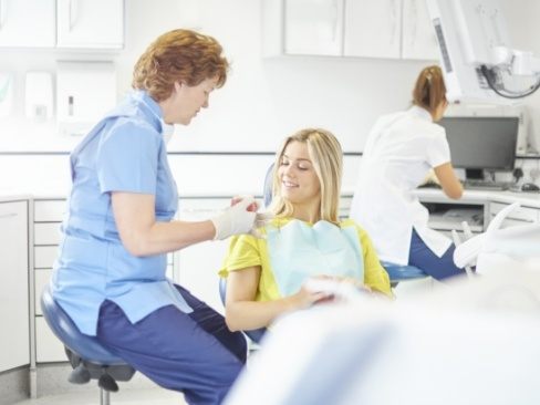 Dental team member and patient looking at smile model and dental crown restoration