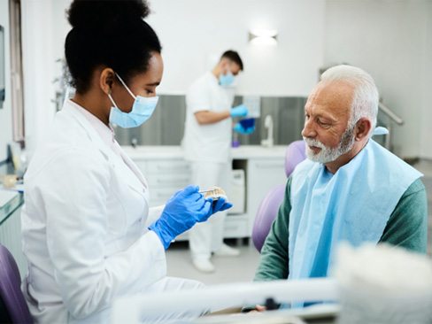 A dentist showing a patient dentures in Dallas