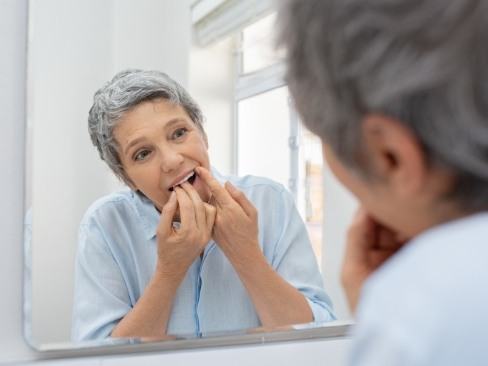 Woman flossing teeth to prevent dental emergencies