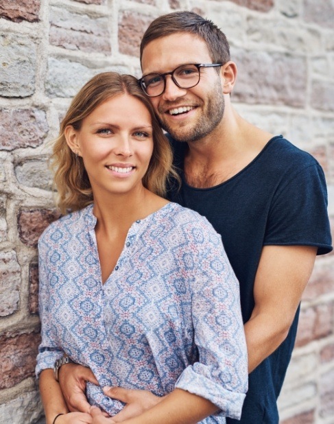 Man and woman with healthy smiles after dental implant tooth replacement