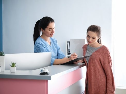 Dental team member and patient reviewing dental insurance forms