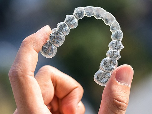 Patient holding up Invisalign in Dallas