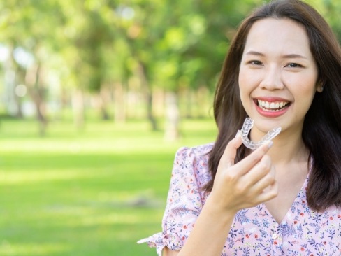 Smiling woman holding an Invisalign aligner tray