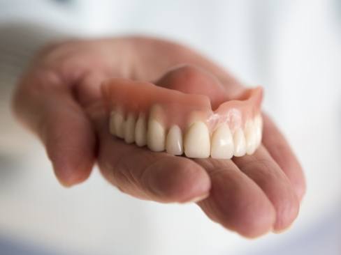 Hand holding a full denture