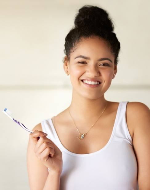 Smiling woman with toothbrush after preventive dentistry visit