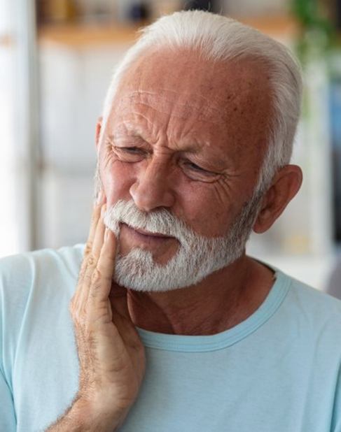 a man holding his cheek due to dental implant failure