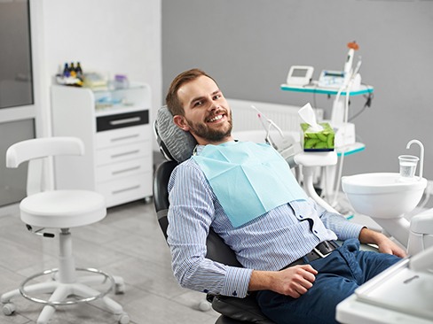 Man in dental chair sitting back and smiling