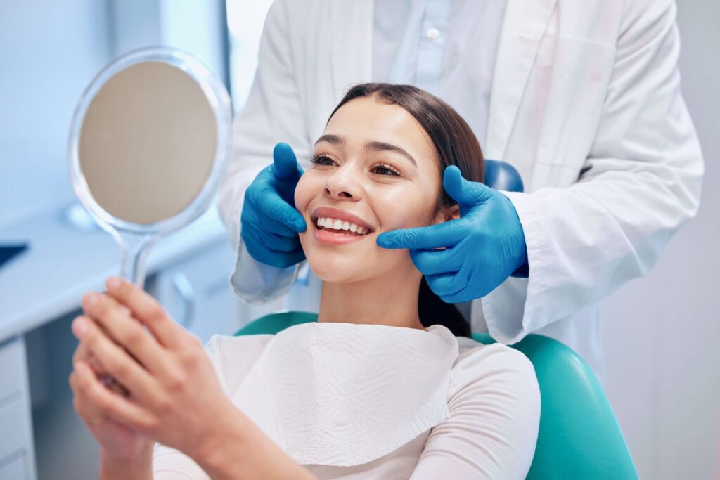 A woman smiling in the mirror at her cosmetic dentistry results.