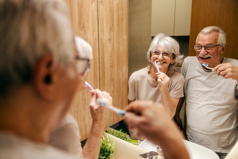 Patients smiling as they brush their dentures